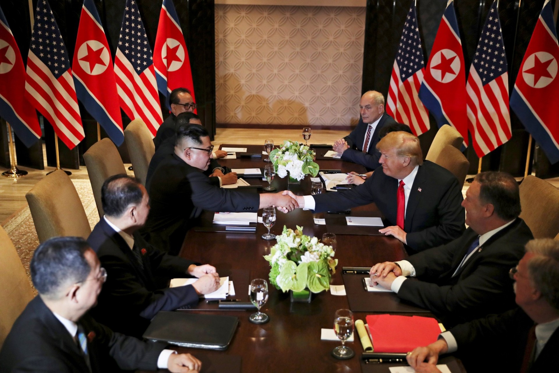Trump and Kim in Singapore shaking hands across conference table